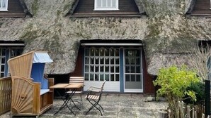A thatched-roof house with a small porch and a window. - Comfortable house Landlust for 4 with garden and terrace in Garding (Garding)