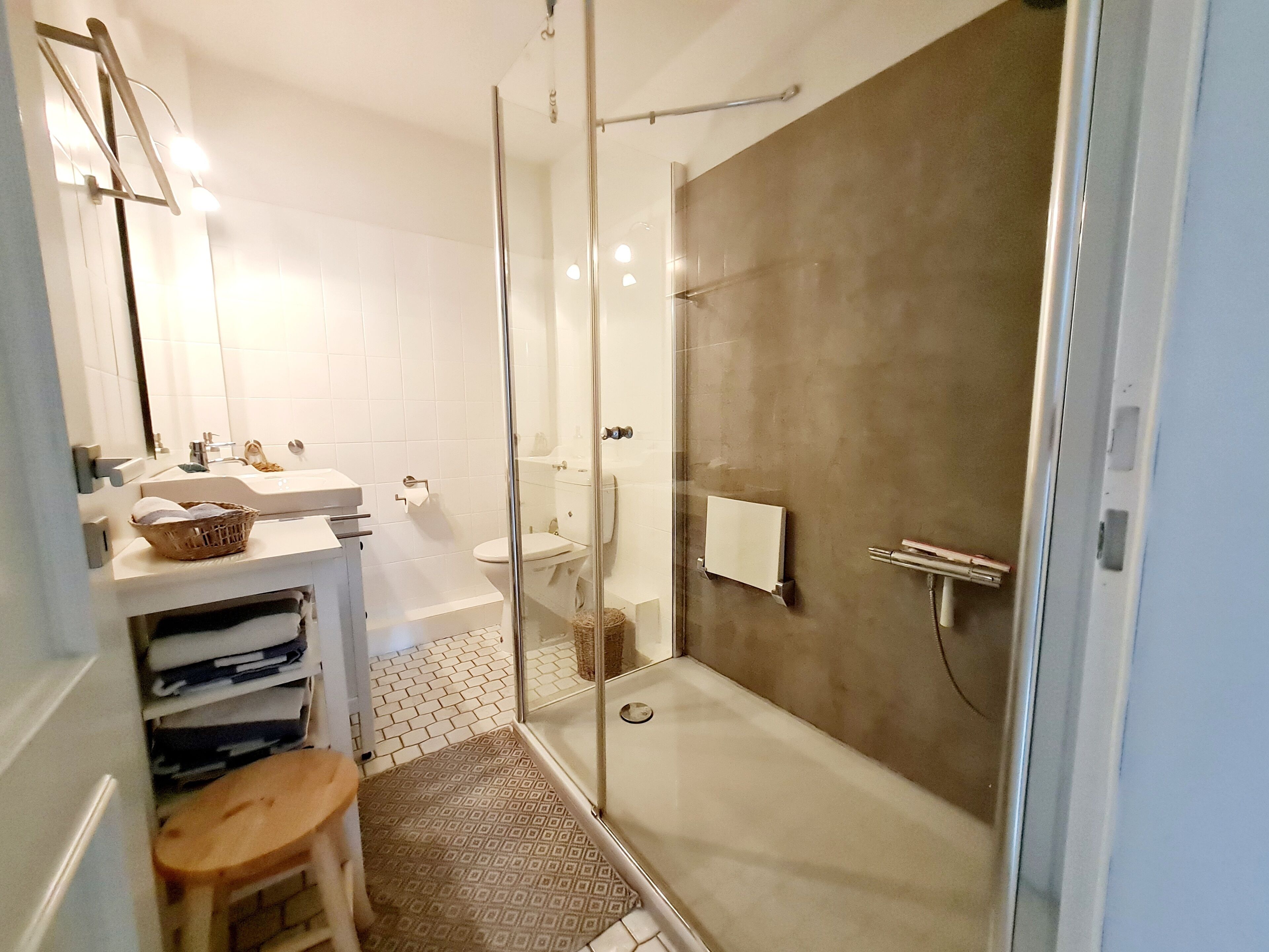 A modern bathroom with a glass-enclosed shower, a white sink, and a mirror.
