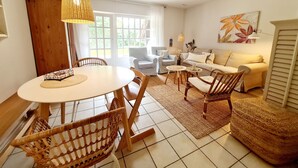 A living room with a round table, two chairs, a sofa, and a large window. - Comfortable house Landlust for 4 with garden and terrace in Garding (Garding)