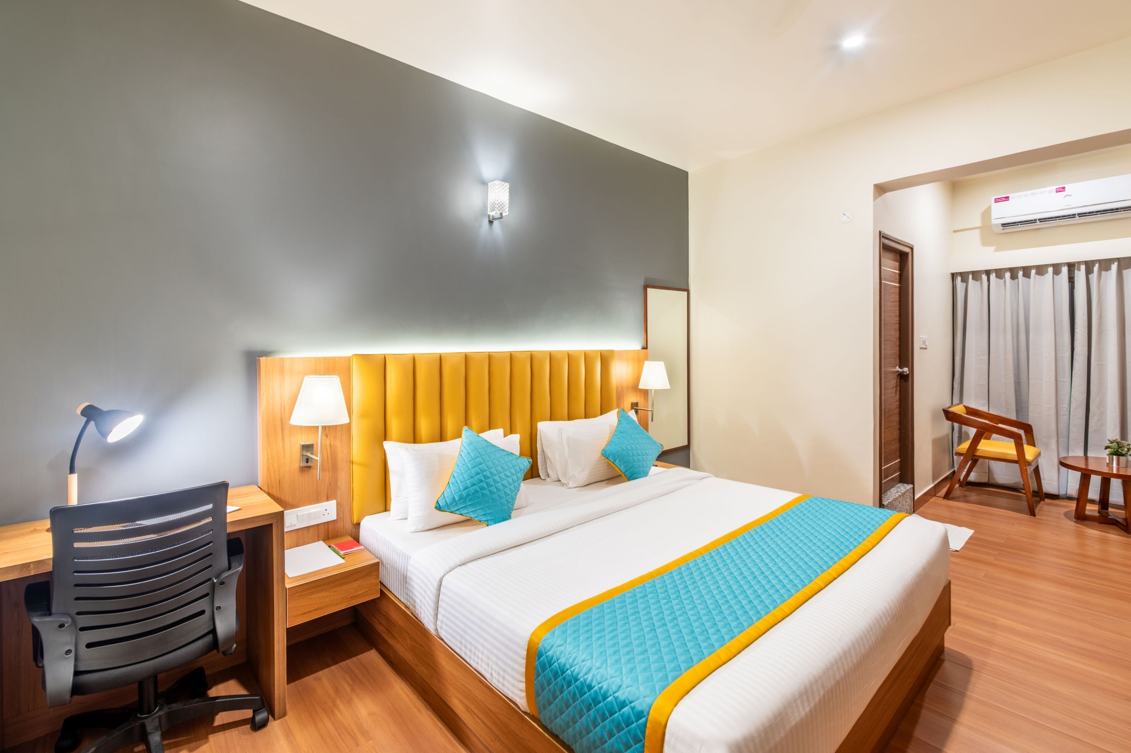 Una habitación de hotel con cama, escritorio, silla y aire acondicionado.