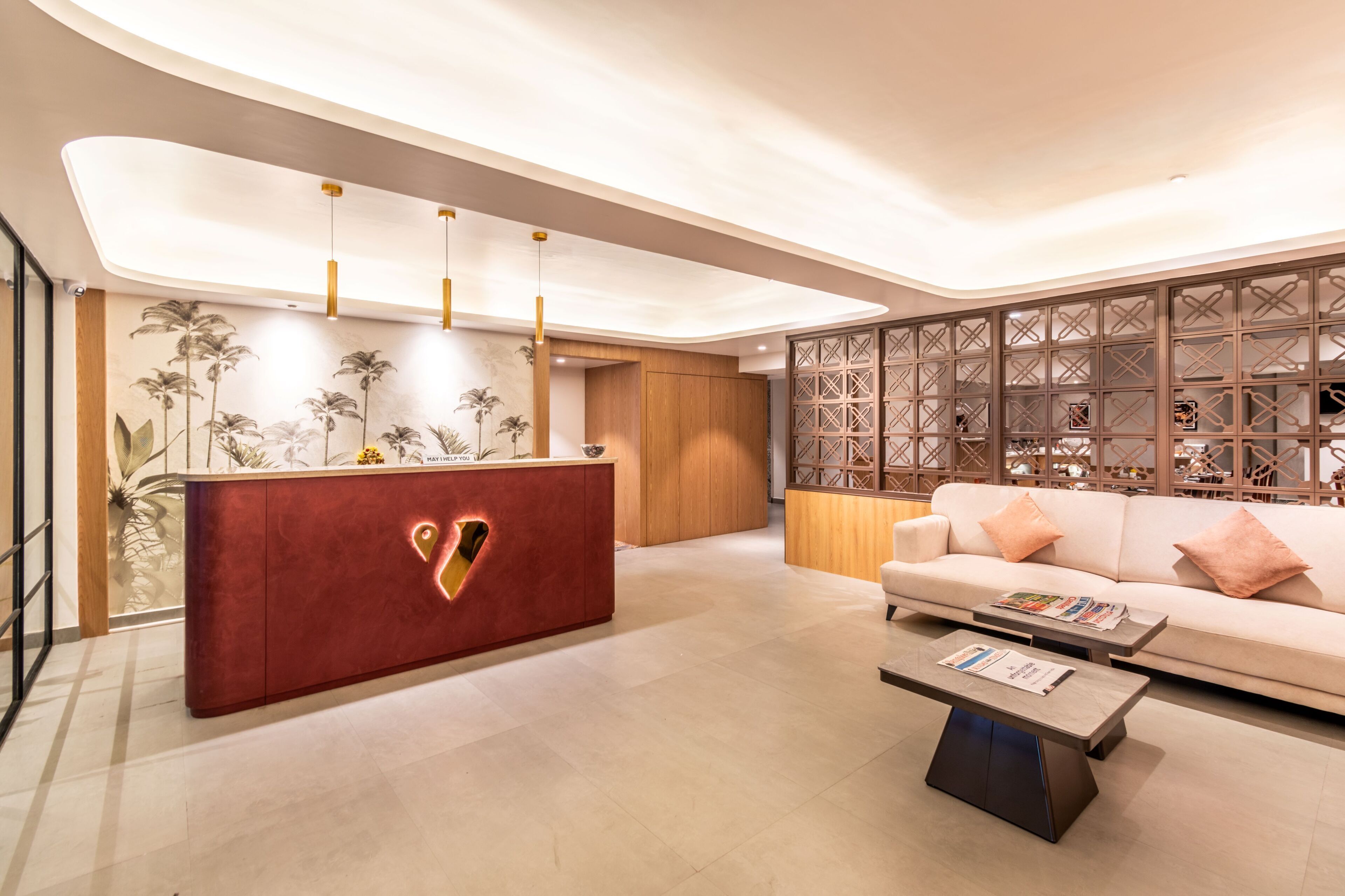 A modern reception area with a red desk, a sofa, and a decorative wall.