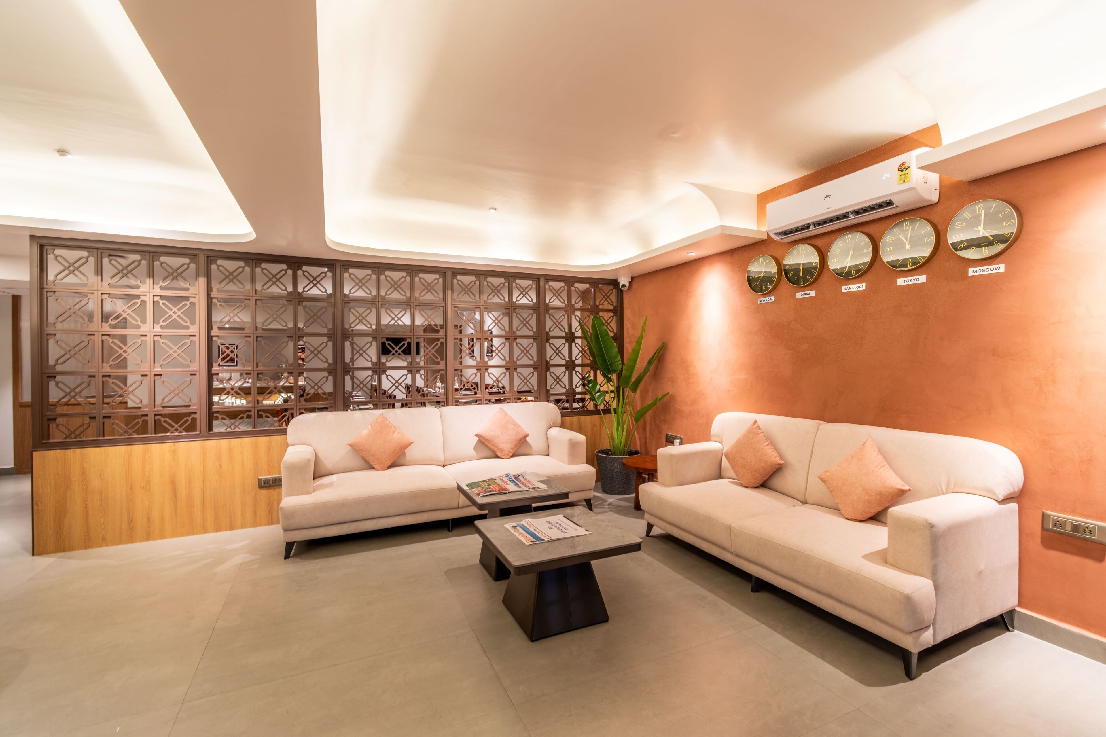 Uma sala de estar moderna com dois sofás, uma mesa de centro e uma parede decorativa com relógios.