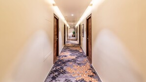Un pasillo con alfombra estampada, puertas de madera e iluminación empotrada.
