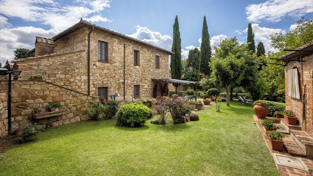 A stone building with a garden, potted plants, and a clear sky. - Maria Gabriella Holiday Home  (Monticchiello)