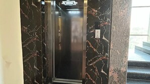 Un ascensor moderno con detalles de mármol y puerta metálica.