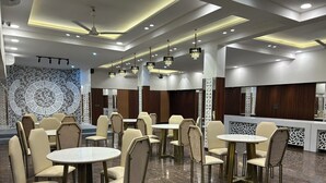 Un comedor moderno con mesas redondas y sillas de respaldo alto, iluminación empotrada en el techo y paneles decorativos en las paredes.