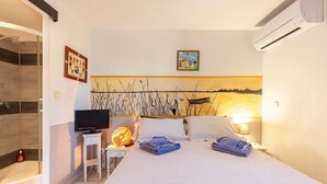 A hotel room with a bed, a television, a bedside lamp, and a wall-mounted air conditioner. - Salamandre Guest Room with Shared Pool, Wi-Fi, and Air Conditioning (Port-Saint-Louis-du-Rhône)