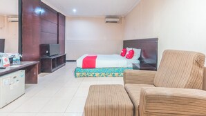 A hotel room with a bed, a TV, a desk, and a chair.