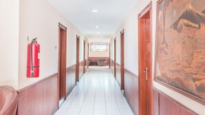 A corridor with wooden doors, a fire extinguisher, and a traditional painting on the wall.