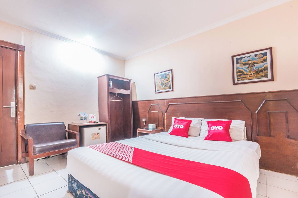 A hotel room with a bed, a desk, a chair, and a wardrobe.