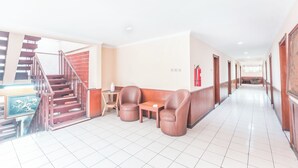 A hotel lobby with a staircase, seating area, and a fire extinguisher.