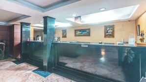 A reception area with a marble floor, a reception desk, a 'Front Office' sign, and framed artwork on the walls.