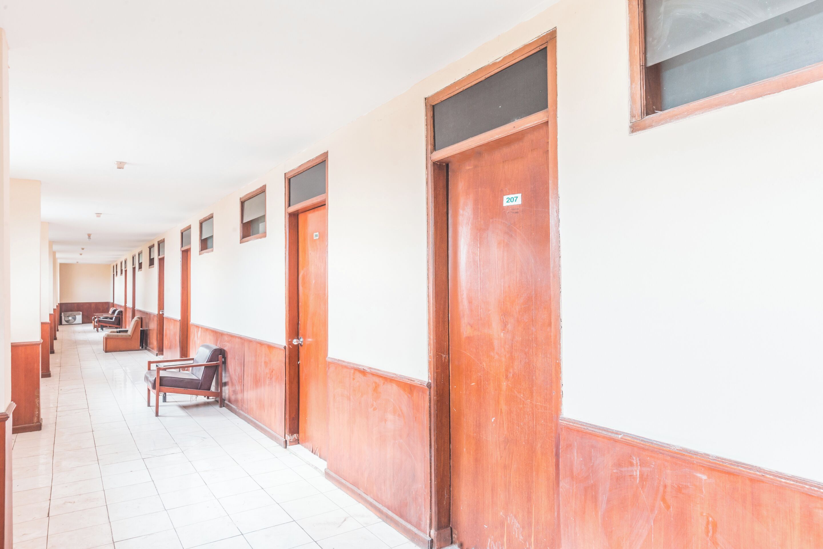 A long, narrow hallway with wooden doors and a tiled floor.