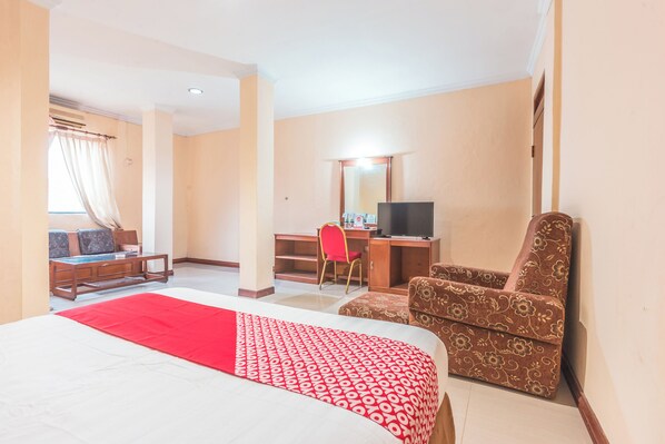 Una habitación de hotel con una cama, un escritorio, un televisor y una silla.