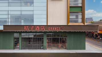 Um hotel chamado 'Kuzuki Hotel Orange' com fachada moderna, grandes janelas e toldo verde.