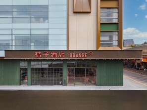 Un hotel llamado 'Kuzuki Hotel Orange' con una fachada moderna, ventanas amplias y un toldo verde.