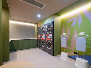 Un cuarto de lavandería con varias lavadoras, un lavabo y dispensadores de toallas.