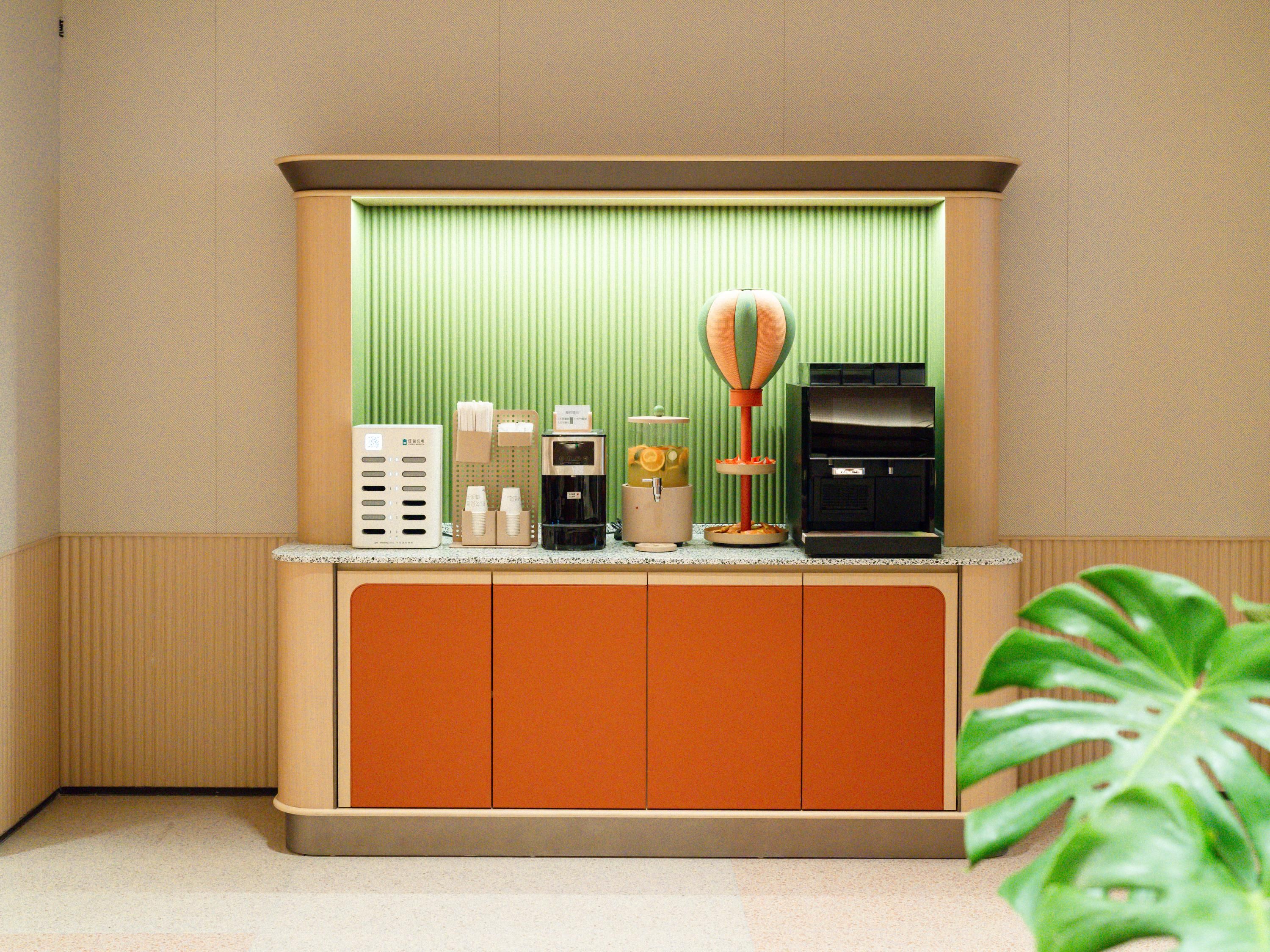 A reception desk with a coffee machine, a small refrigerator, and a decorative plant.