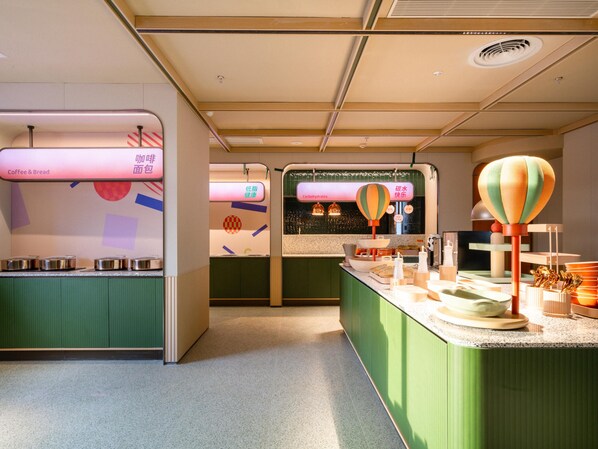 Interior moderno de una cafetería con armarios verdes, una barra con diversos productos y una pared mostrando opciones de menú en varios idiomas.