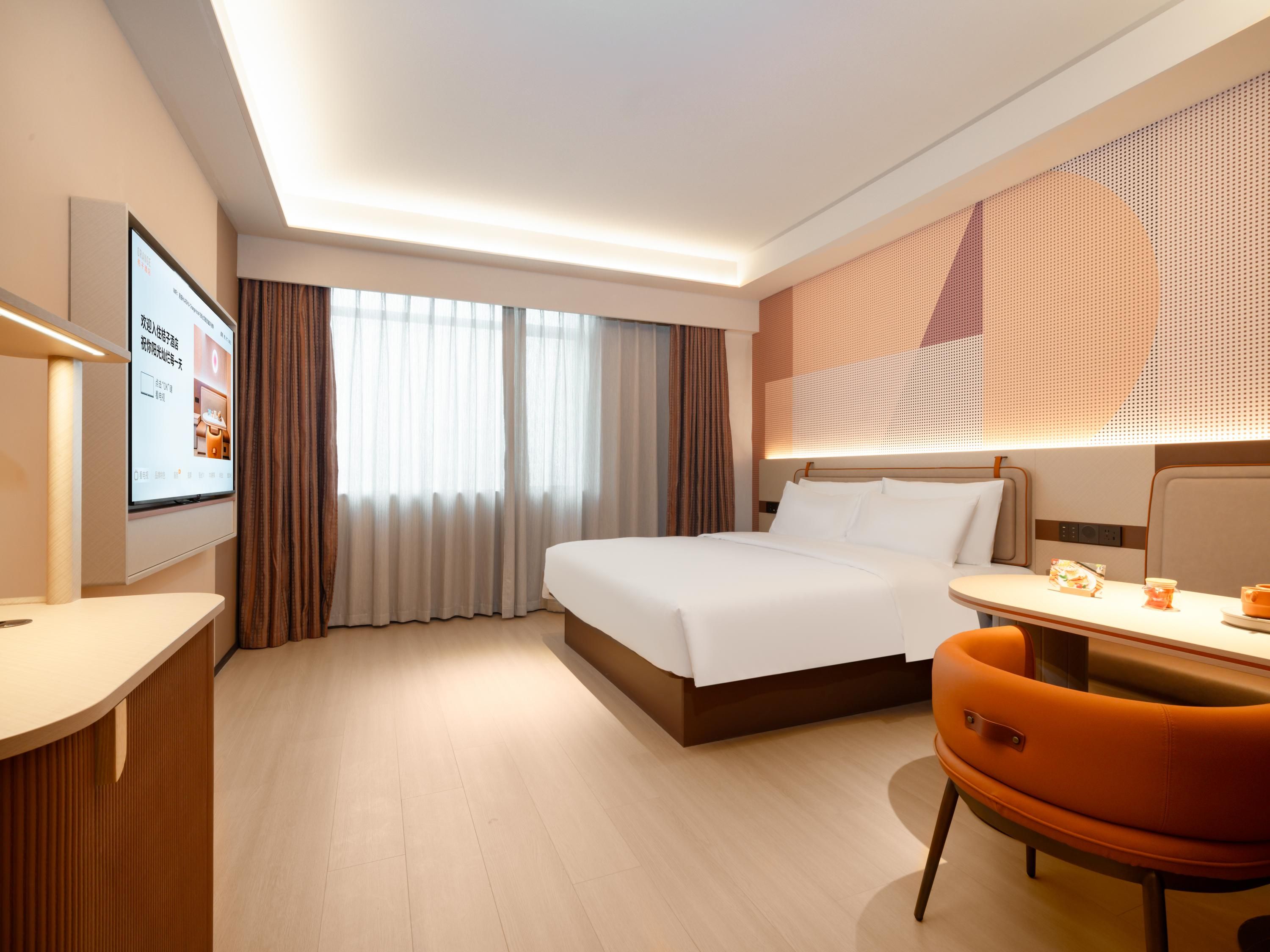 Quarto de hotel com cama, escrivaninha, cadeira, televisão e janela com cortinas.