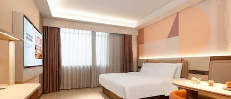 A hotel room with a bed, a desk, a chair, a TV, and a window with curtains.