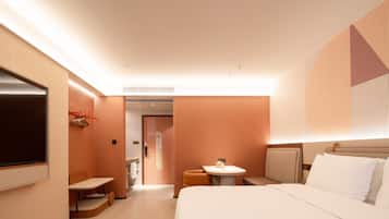 Habitación de hotel con cama, una mesita, televisión y baño visible a través de una puerta abierta.