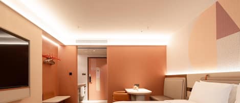 Habitación de hotel con cama, una mesita, televisión y baño visible a través de una puerta abierta.