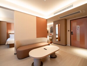 Habitación de hotel moderna con sofá, una mesita, un espejo, baño y puerta.