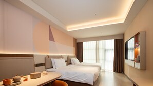 Una habitación de hotel con cama, escritorio, silla, televisor y un amplio ventanal.