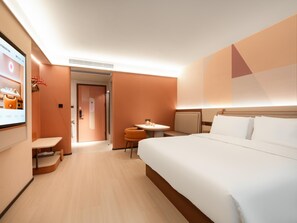 A hotel room with a large bed, a small table, a chair, and a TV screen. - Orange Guangzhou Panyu Chimelong Wanbo Center (Guangzhou)