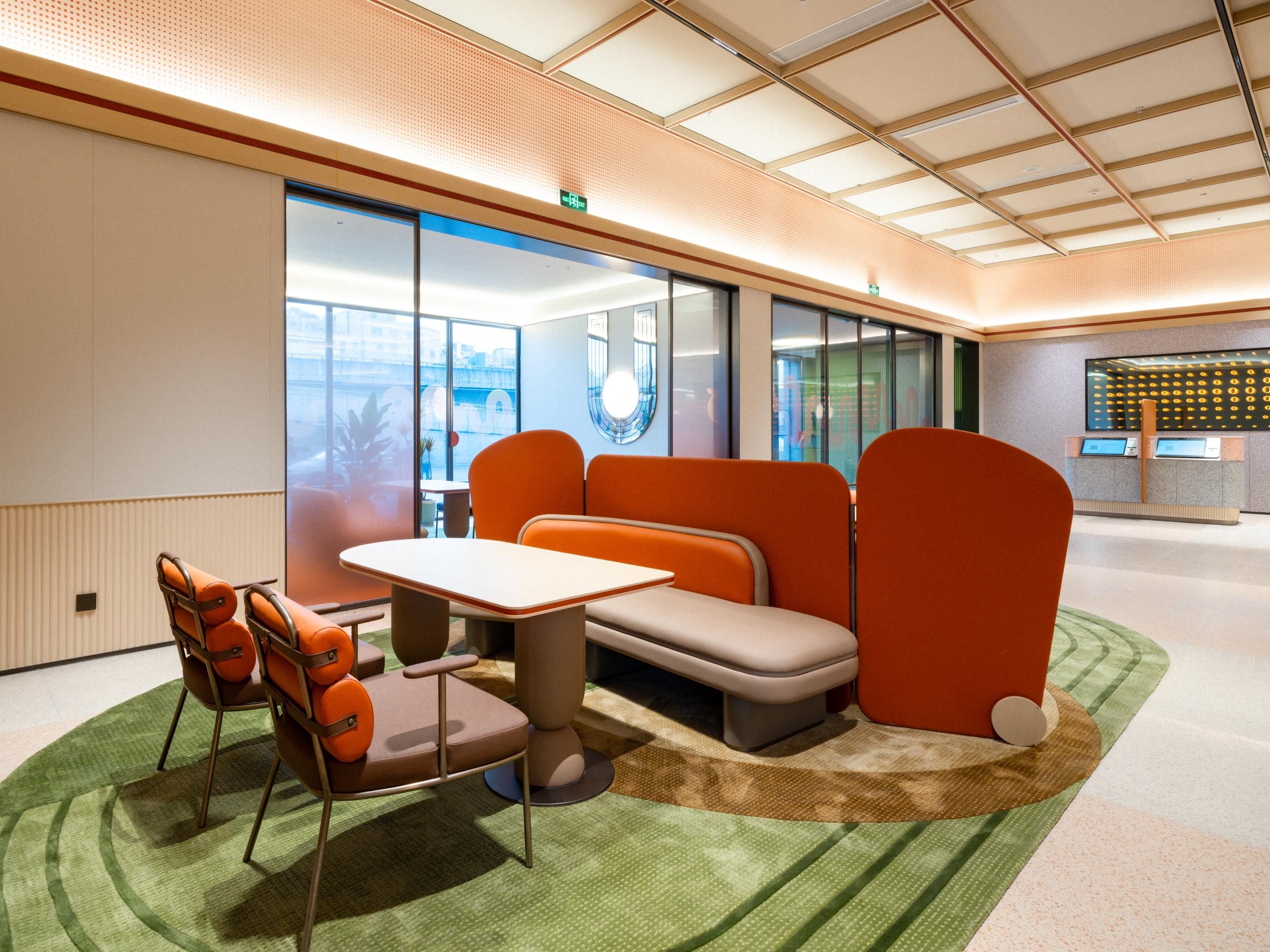 A modern office space with a reception area, seating arrangements, and a view through large windows.
