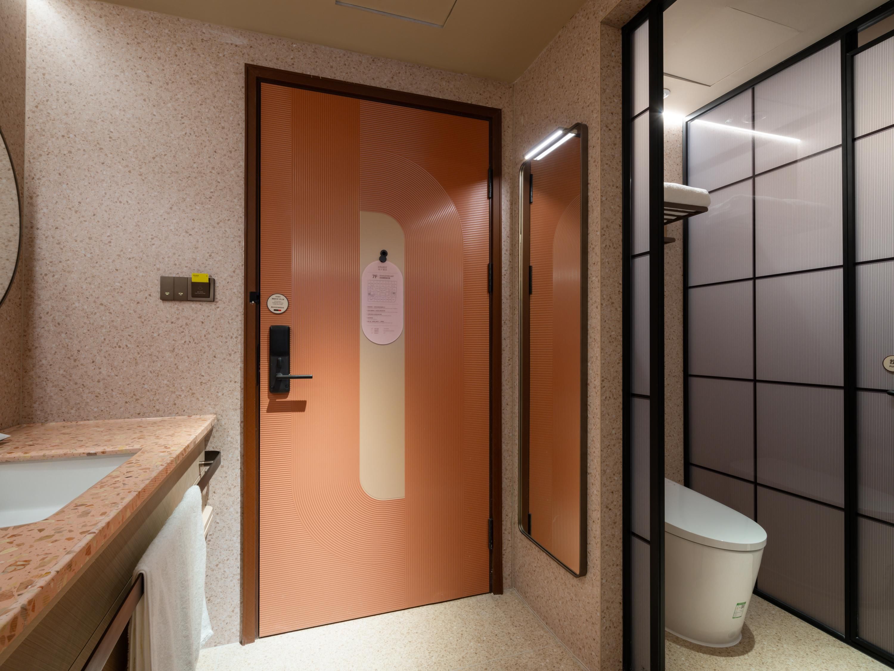 Un baño con puerta de madera, un lavabo, un inodoro y un espejo.