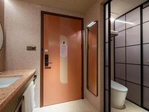 Un baño con puerta de madera, un lavabo, un inodoro y un espejo.
