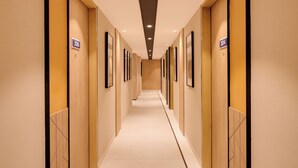 Ein Hotelkorridor mit Holzwandverkleidung, nummerierten Türen und gerahmten Bildern an den Wänden.