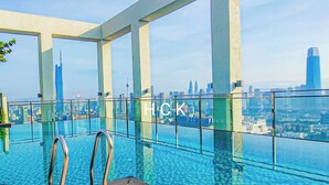 An infinity pool with a city skyline view, metal railings, and a clear sky. - KL City View at Trion 2 by HCK (Kuala Lumpur)