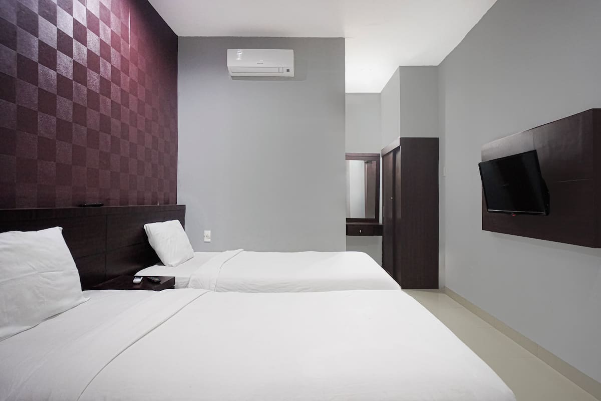 Ein Hotelzimmer mit zwei Betten, einem Wand-Fernseher und einer Klimaanlage.