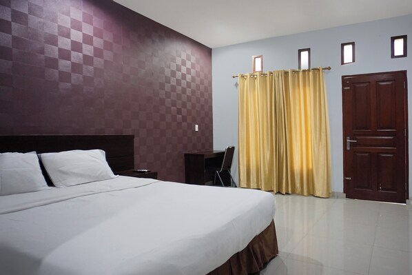 Une chambre d’hôtel avec un grand lit, un bureau et une armoire.