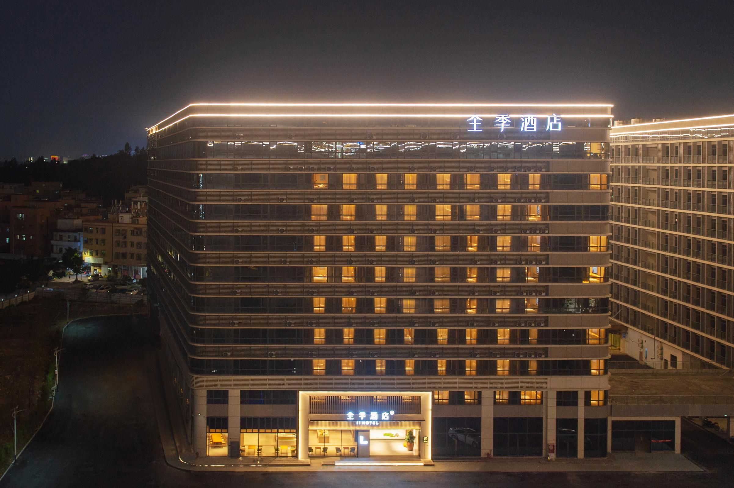 A multi-story hotel with a modern design, featuring a prominent entrance and illuminated signage.