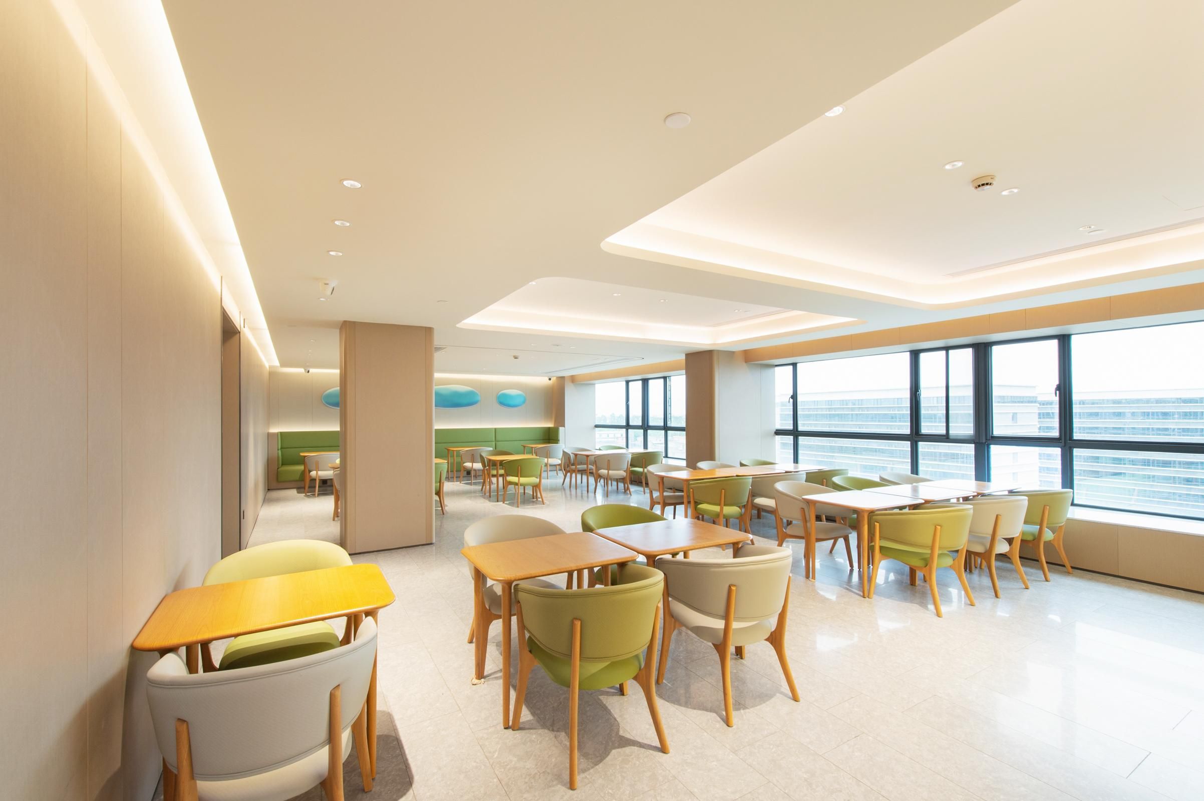 Un comedor moderno con mesas y sillas, ventanas amplias y vista al mar.