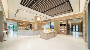 A modern hotel lobby with a central reception desk, a digital display, and a seating area. - Ji Hotel Guangzhou Baiyun Airport Terminal 2 (Guangzhou)