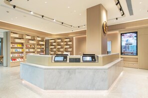 A modern reception desk with digital displays, a large screen, and a well-organized bookshelf. - Ji Hotel Guangzhou Baiyun Airport Terminal 2 (Guangzhou)