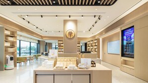 A modern hotel lobby with a central reception desk, seating area, and large windows offering a view of the outside. - Ji Hotel Guangzhou Baiyun Airport Terminal 2 (Guangzhou)