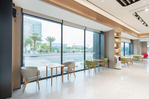 A modern hotel lobby with large windows, seating areas, and a coffee machine. - Ji Hotel Guangzhou Baiyun Airport Terminal 2 (Guangzhou)