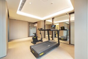 A modern hotel room with a treadmill, exercise bike, and a large mirror reflecting the room. - Ji Hotel Guangzhou Baiyun Airport Terminal 2 (Guangzhou)