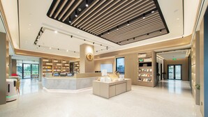 A modern hotel lobby with a central reception desk, a digital display, and a seating area. - Ji Hotel Guangzhou Baiyun Airport Terminal 2 (Guangzhou)