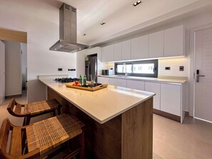 Una cocina moderna con una isla central, electrodomésticos de acero inoxidable y un amplio ventanal que proporciona luz natural.