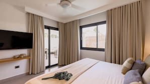 Habitación de hotel con una cama grande, un televisor de pantalla plana en la pared y un ventilador de techo.