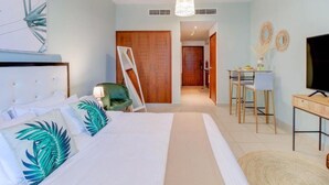 Ein Schlafzimmer mit Bett, Schreibtisch, Stuhl, Fernseher und einer Tür zu einem anderen Raum.