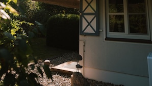 A house with a thatched roof, a window with shutters, and a small porch area.