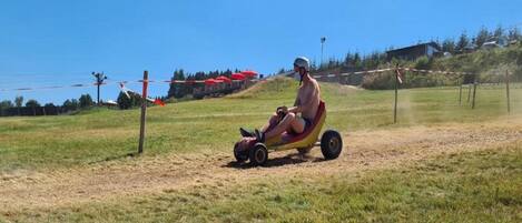 A person riding a small, red and yellow vehicle on a dirt path.
